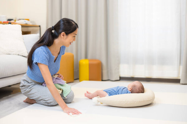 Caring mother cleaning baby playpen in cozy home