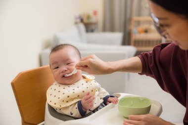Anne bebeği yumuşak yiyecekle besliyor.