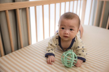 Bebek dönüyor ve yatakta top oynuyor.