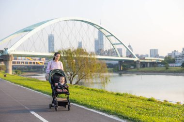 Anne Bebek Arabasıyla Nehir kenarında Yürüyor