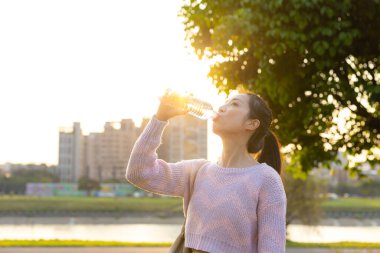 Gün batımında Nehir kenarında Su İçen Genç Kadın