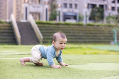 Küçük bebek taze çimenlerde doğayı keşfediyor.
