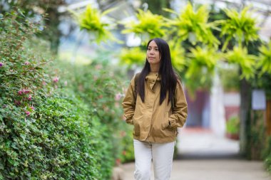 Genç bir kadın huzurlu bahçe yolunda yürüyor.