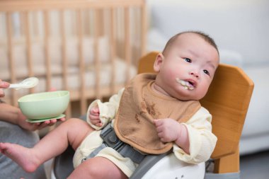 Bebek sandalyede mutlu bir şekilde yemek yiyor
