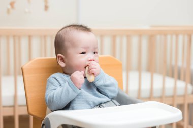 Bebek sandalyede oturup abur cubur yiyor