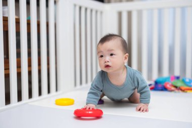 Bebek paspasın üzerinde sürünüyor, oyuncaklarla