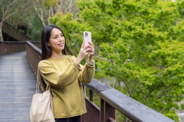 Yürüyüş yolunda telefonla fotoğraf çeken bir kadın.