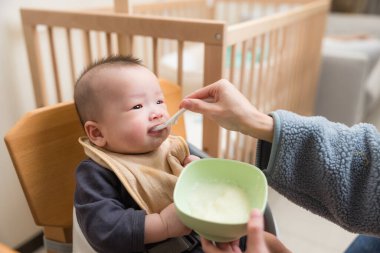 Mutlu bebek yüksek sandalyede yemek yiyor.