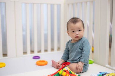 Bebek beşikte oturuyor oyuncakla oynuyor