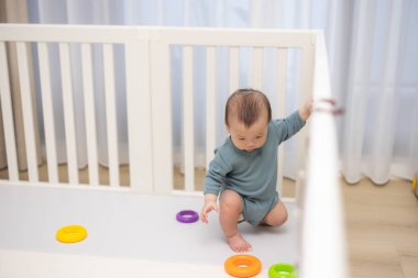 Küçük bebek beyaz beşiğin içinde durmayı öğreniyor.