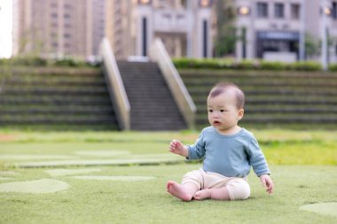 Bebek yeşil çimlerde sessizce oturuyor.