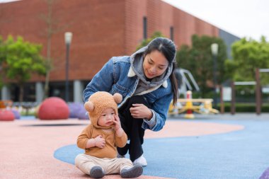 Annem parkta ayı şapkası takmış bebekle oynuyor.