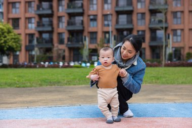 Anne kucağında bebek, yürümeyi öğreniyor.