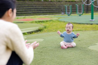 Küçük bebek çimenlerde sürünüyor ve annesi izliyor.