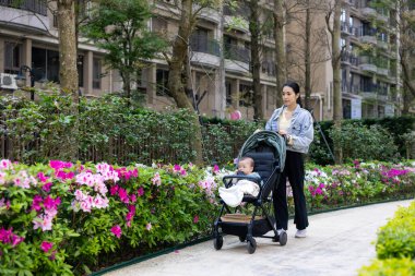 Anne bahçede bebek arabasıyla yürüyor.