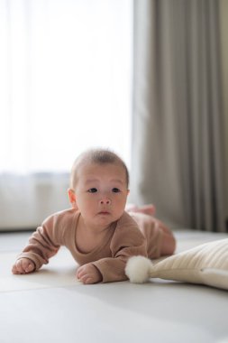 Evdeki yumuşak paspasın üzerinde emekleyen küçük bebek.