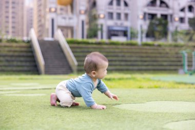 Bebek yeşil çimlerde tek başına sürünüyor.