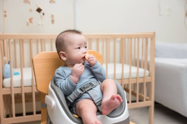 Küçük bebek sandalyede yemek yiyor.