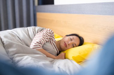 Huzurlu genç kadın rahat bir yatakta uyuyor.