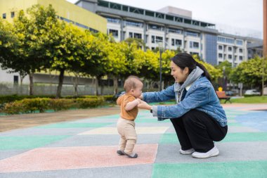 Küçük çocuk annesinin desteğiyle yürüyor.
