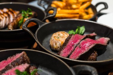 Dökme demirle servis edilen dilimlenmiş sulu biftek.