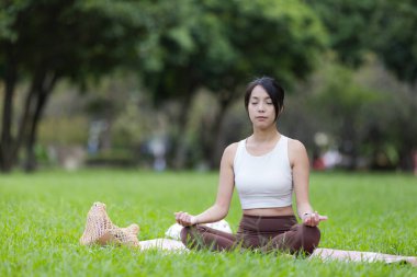 Spor kadını parkta meditasyon ve farkındalık yapıyor.