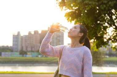 Parkta Gün Batımında Su İçen Kadın