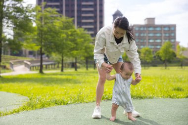 Anne oğluna ilk kez yürümeyi öğretiyor.