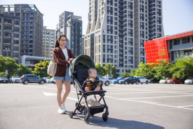 Annem bebek arabasıyla dışarıda yürüyor.