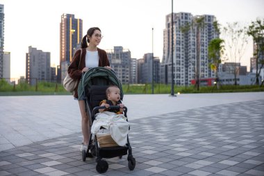 Bebek arabasını kaldırıma iten kadın.