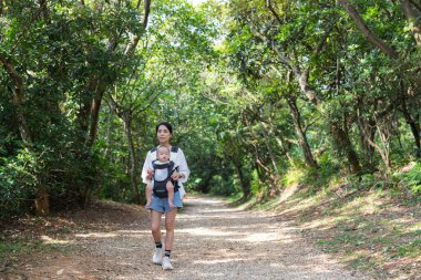 Anne, bebeğini taşıyan oğluyla yürüyüşe çıktı.