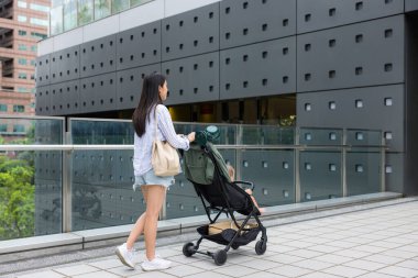 Anne bebeğiyle şehirde bebek arabasında yürür.