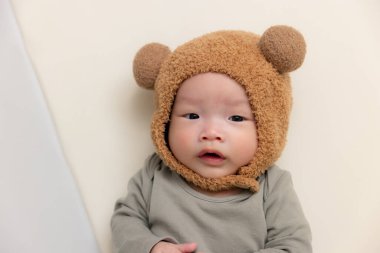 Sevimli ayı şapkalı küçük bebek ve yatakta yatıyor.