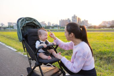 Anne gün batımında bebek arabasında bebeğe bakıyor.