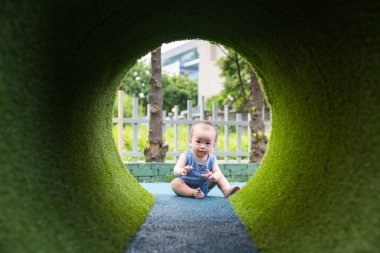 Küçük bebek oğlu dışarıda tünel oyunu oynuyor.