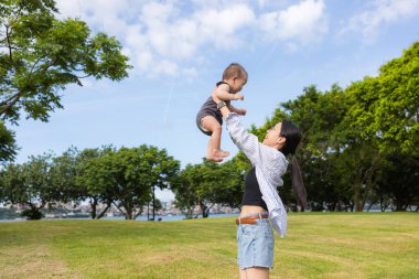 Küçük oğlu annesiyle birlikte parkta uçuyor.