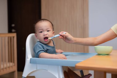 Bebek evde kaşıkla püre yiyor.