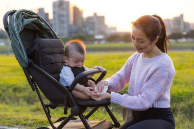 Anne parkta oğlunu peçeteyle temizliyor.