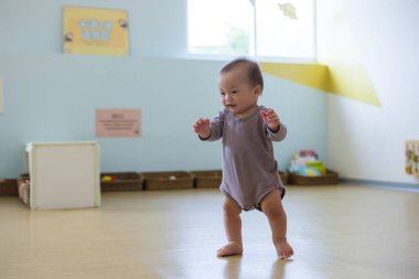 Küçük Asyalı bebek renkli oyun evinde oynuyor.
