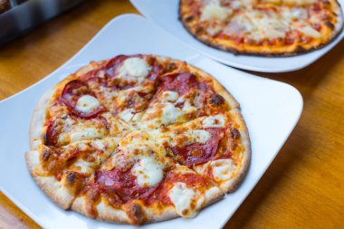 Beyaz tabak restoranında servis edilen taze pizza dilimi.