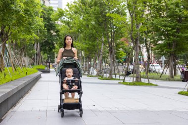 Annem bebekle bebek arabasının parkında yürüyor.