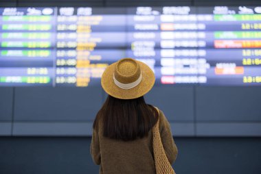 Havaalanında uçuş çizelgesini kontrol eden kadın.