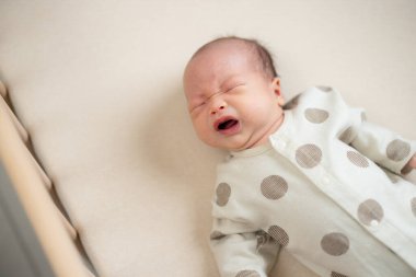 Yeni doğmuş bebek yatakta ağlıyor.