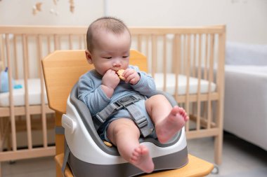 Küçük bebek pirinç krakerini ye ve sandalyeye otur.