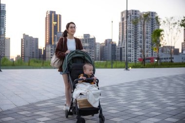 Anne ve oğlu bebek arabasıyla dışarı çıkıyorlar.