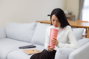 Evde plastik geri dönüşüm şişesiyle su içen kadın.