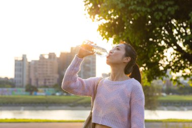 Yeşil parkta tatlı suyun tadını çıkaran bir kadın.