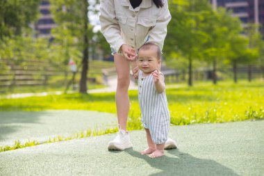 Anne ve oğlu parkta birlikte oynuyorlar.