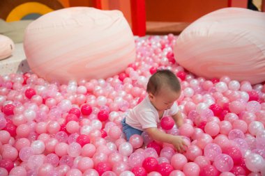 Sevimli bebek pembe top havuzunda eğleniyor.