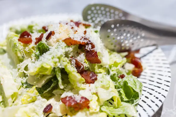 Beyaz tabakta servis edilen taze sezar salatası.